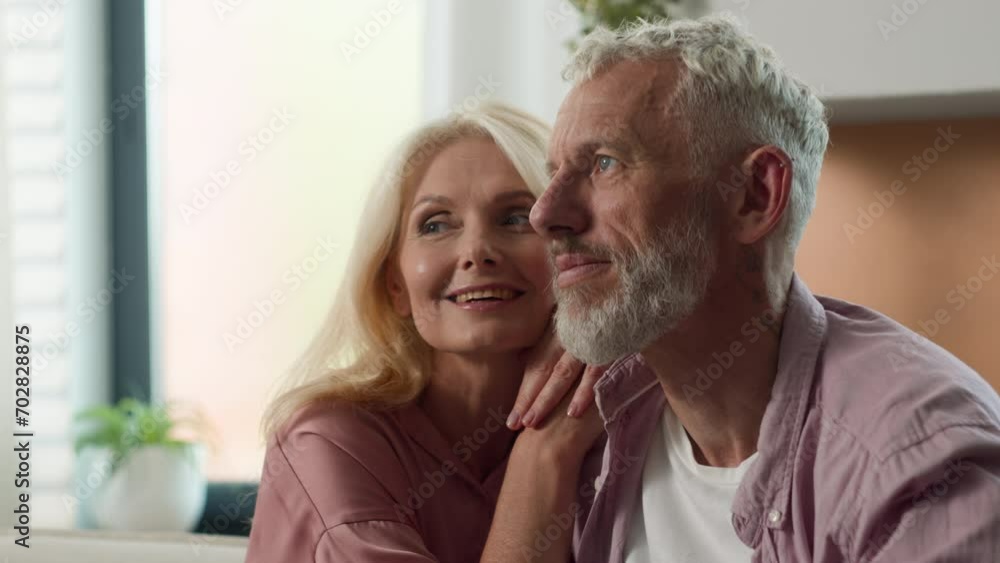 Happy smiling dreaming Caucasian married family couple in love man woman husband wife hugging hug cuddle in living room together bonding relationship mature homeowners apartment renters enjoying dream