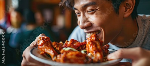 Happy Asian man eating BBQ chicken wings in restaurant. with copy space image. Place for adding text or design photo