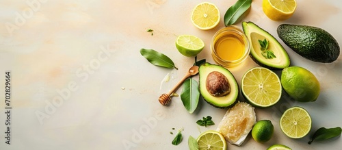 Homemade cosmetic mask with fresh avocado green lime slices fruits ingredients on white desktop jars with essential oil and honey skincare hair treatment. with copy space image