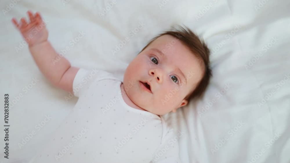 Vidéo Stock A newborn baby lies on his back on a white bed and looks at