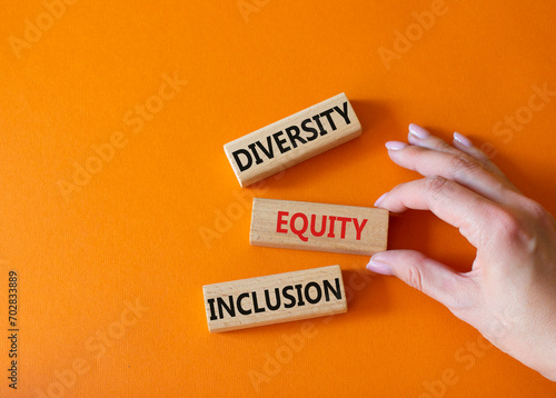 Diversity Equity Inclusion symbol. Concept words Diversity Equity Inclusion on wooden blocks. Beautiful orange background. Businessman hand. Business and Diversity Equity Inclusion concept. Copy space