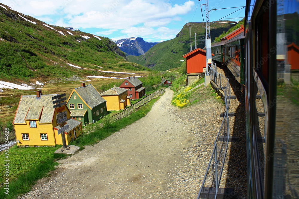 Norway. The train travels against the background of a picturesque village of wooden colored houses among the mountains
