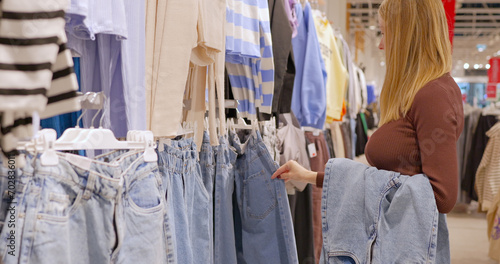 A young woman chooses jeans in a clothing store