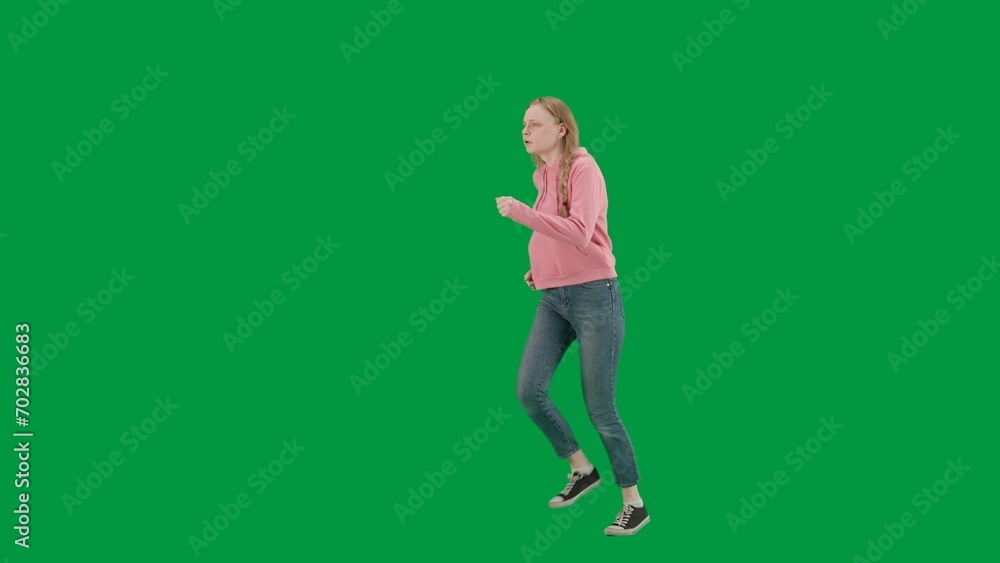 Portrait of victim on chroma key green screen background. Young girl running, scared expression, looking around, running faster from danger. Half turn.