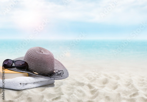 Buch und Sonnenhut an einem Sandstrand