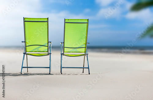 Grüne Liegestühle an einem Sandstrand