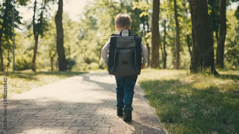 Back view nursery school boy walking park alley, beautiful summer nature around Back view nursery school boy walking park alley, beautiful summer nature around