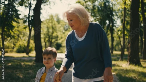 Happy senior woman walking in park with little grandson, leisure together photo