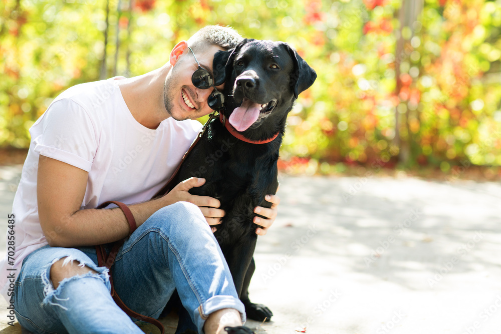 Guy in sunglasses hugs his dog in autumn park Guy in sunglasses hugs his dog in autumn park