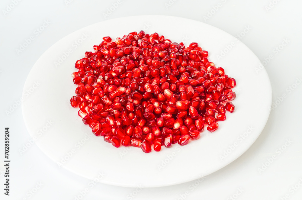 White bowl with red pomegranate seeds on a white background. Raw tasty fresh berries for eating. White bowl with red pomegranate seeds on a white background. Raw tasty fresh berries for eating.