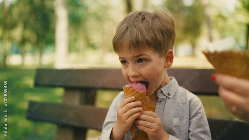 Cute little boy eating delicious ice cream on bench in park enjoying sweet treat Cute little boy eating delicious ice cream on bench in park enjoying sweet treat