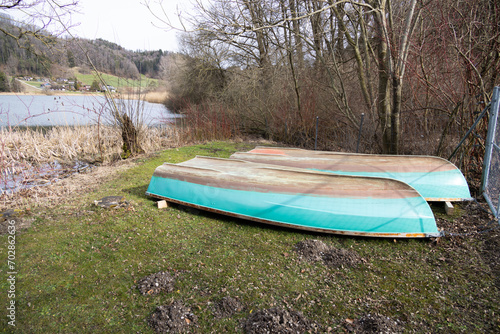 Inverted turquoise blue fishing boats, green meadow, cloudy during the day, without people