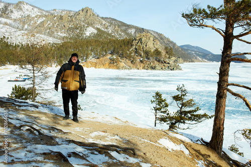 A man is a traveler behind the transparent ice floe of the frozen Lake Baikal. Winter trip.  © Viktoriya