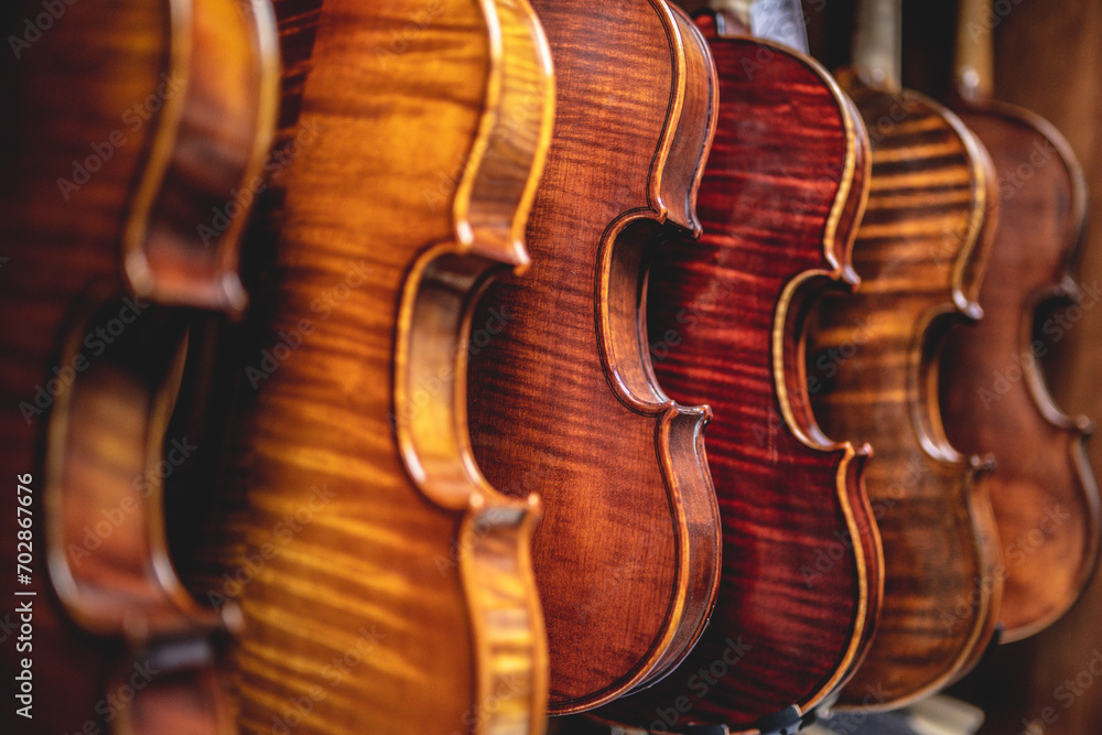 Obraz premium Row of multiple violins hanging on the wall, musician workshop