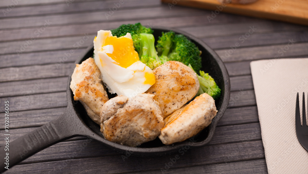 Healthy appetizer of chicken pieces with broccoli and poached egg in small cast iron skillet Healthy appetizer of chicken pieces with broccoli and poached egg in small cast iron skillet