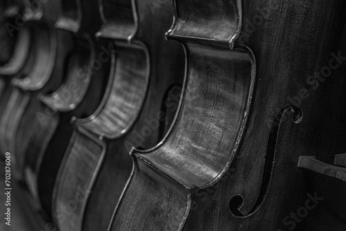 close up of a Row of multiple cellos standing on the floor at a musician workshop