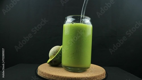 Rotating display of avocado juice on black background. photo