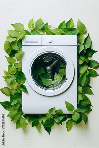 Washing machine with green leaves around it. Eco cleaning, eco friendly washing concept. Environmentally friendly bio natural home cleaning. Plants near modern washing machine. Spring cleaning theme.
