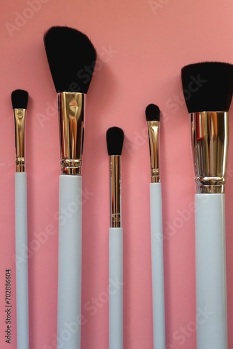 Various different make up brushes on pink background. Top view.