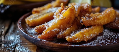 Popular street food in Malaysia, Indonesia, and South East Asia: pisang goreng, fried banana covered in sweet batter, served on a wooden table. photo