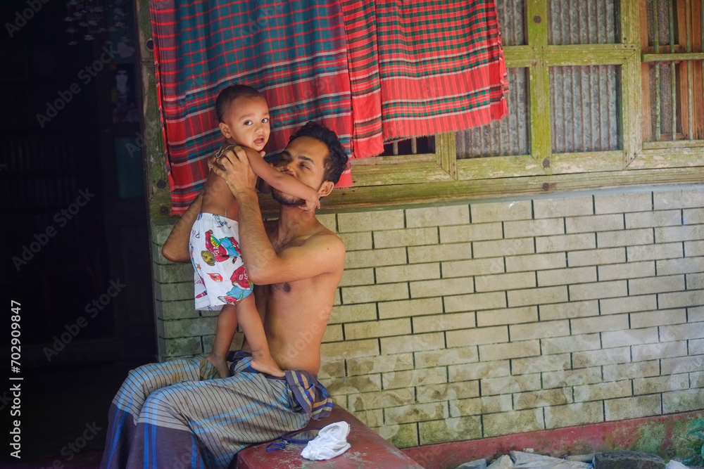 Bangladeshi rural family members are having fun together , father with son