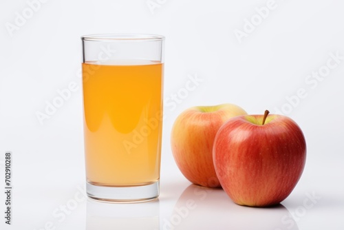 glass of apple juice on a white background and apples nearby