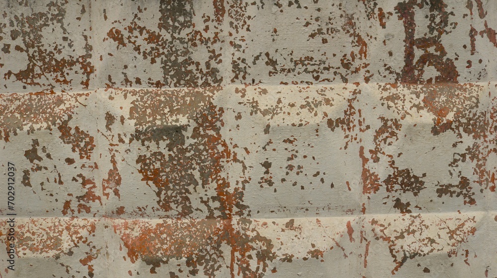 shabby concrete wall with square bumps and flaking paint as rough texture, cracked light paint on a surface of hard solid gray material as background graphic resource