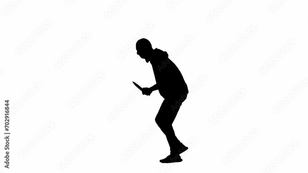 Black silhouette of thief on isolated white background. A male robber in a hoodie and balaclava walks with a knife in his hands, preparing to commit a crime. Side view. Black silhouette of thief on isolated white background. A male robber in a hoodie and balaclava walks with a knife in his hands, preparing to commit a crime. Side view.