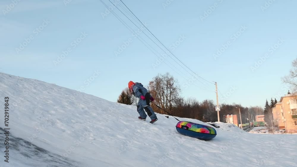 Portrait of a child playing in the snow in winter, sliding down the hill on a tubing. High quality Portrait of a child playing in the snow in winter, sliding down the hill on a tubing. High quality