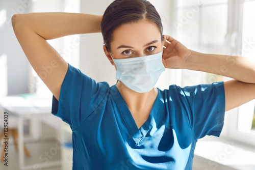 In the hospital, a woman doctor, wearing a protective face mask with a serious gaze into the camera. Portrait of nurse showing concern about healthcare of staff and physician. photo