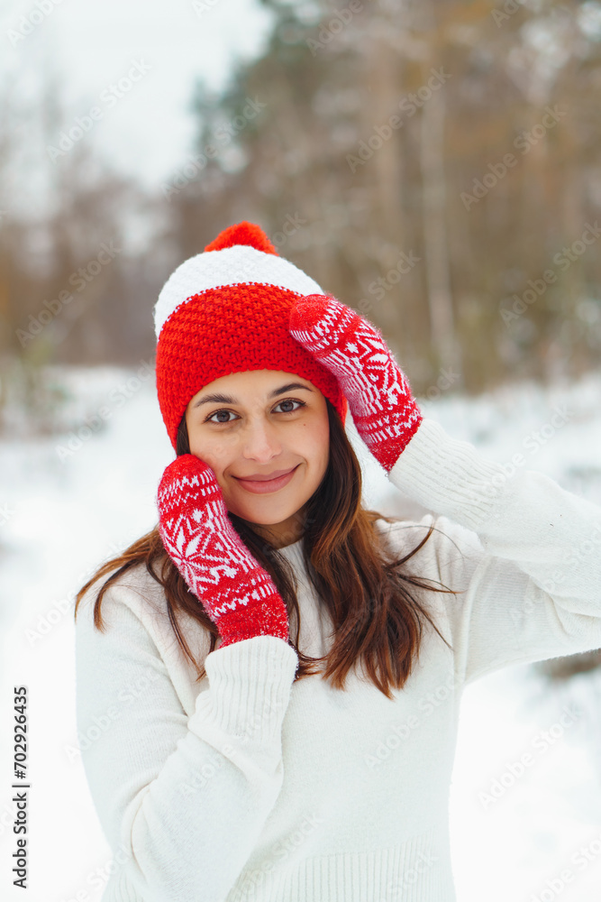 Young beautiful woman in red knitted hat and mittens in winter forest. Snowy day autdoors Young beautiful woman in red knitted hat and mittens in winter forest. Snowy day autdoors