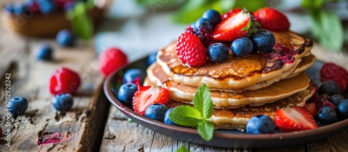 Delicious berry-topped pancakes on wooden table in photo.