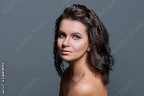 Headshot portrait of young woman with hairstyle makeup on gray background