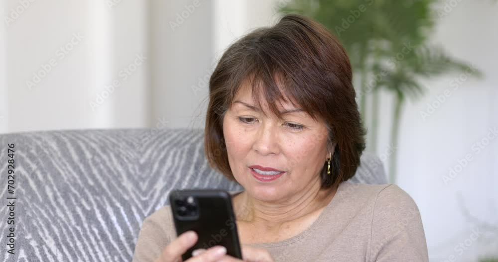 Attractive woman holding enjoying using mobile cell phone texting reading email relaxing sitting on chair at home closeup. Attractive woman holding enjoying using mobile cell phone texting reading email relaxing sitting on chair at home closeup.