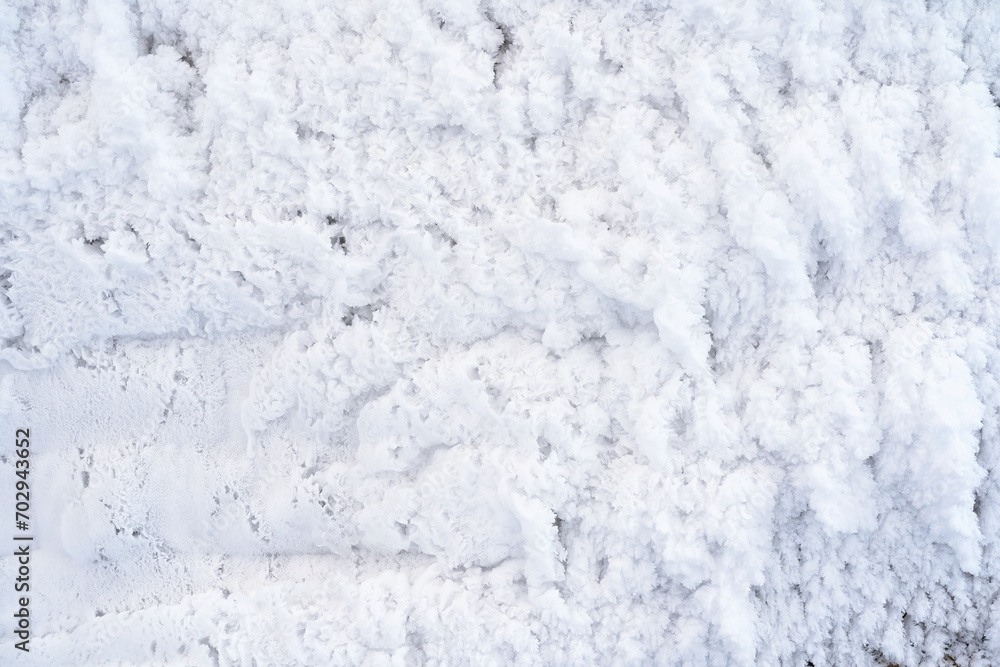 The surface of the building wall is completely covered with white frost. There are beautiful openwork snow flakes. Close-up. Background. The surface of the building wall is completely covered with white frost. There are beautiful openwork snow flakes. Close-up. Background.