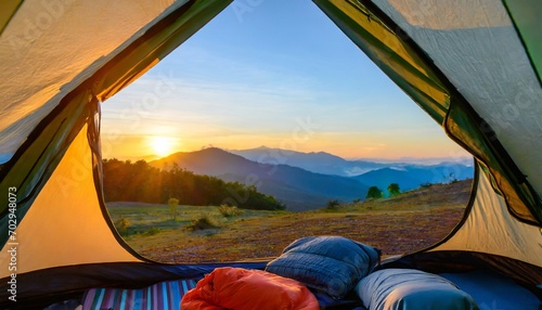 view of the serene landscape from inside a tent camping at campsite with sleeping bags stunning sunrise