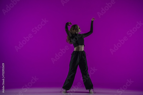 Energetic contemporary dance in purple studio light: young girl in black clothes shows grace and passion for dance. Full length. Promo or commercial.
