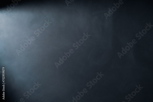 Beams of light from spotlight in dark studio with smoke. Stream of light from movie spotlight on black background. Particles of smoke floating in the rays of light.