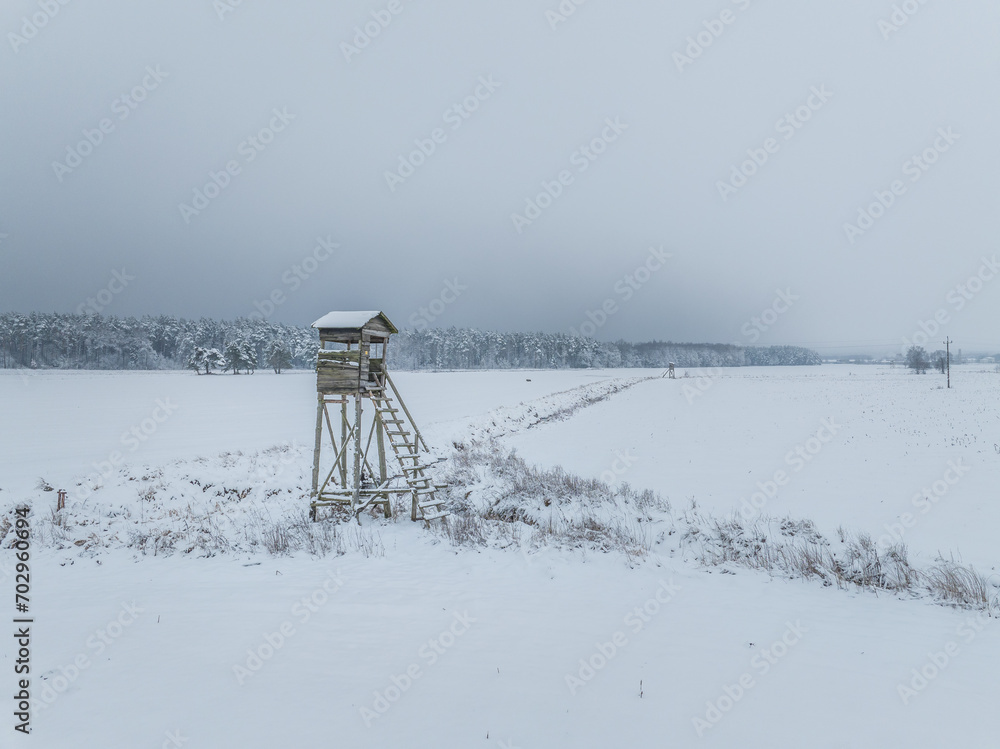 A vacant hunting stand in winter, located at the edge of a forest in Poland, embodying a quiet and serene winter scene. A vacant hunting stand in winter, located at the edge of a forest in Poland, embodying a quiet and serene winter scene.