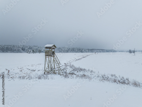 A vacant hunting stand in winter, located at the edge of a forest in Poland, embodying a quiet and serene winter scene.