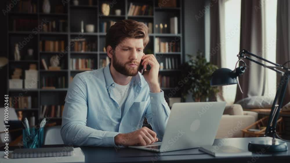 young busy man sits at desk at home office and remote work at laptop, pick up phone call, gets failure betrayal news and gets angry, shouts aggressively and throws mobile away young busy man sits at desk at home office and remote work at laptop, pick up phone call, gets failure betrayal news and gets angry, shouts aggressively and throws mobile away