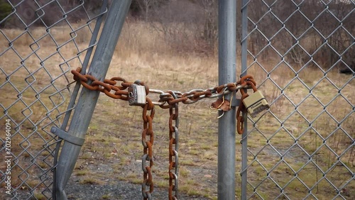 Rusty chain with two locks keeping an old fence closed
