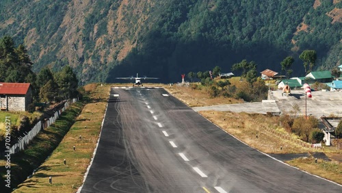 Passenger or cargo turboprop aircraft lands on short and dangerous runway at Lukla airport Nepal. Transportation of goods and tourists by air in Himalayan mountains on way to summit mount Everest photo