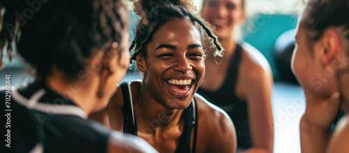 Young woman laughing with diverse friends on a gym floor after exercise.
