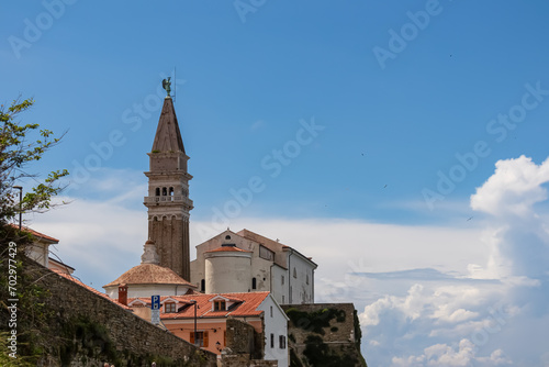 Panoramic view of church Duomo di San Giorgio in coastal town Piran, Slovenian Istria, Slovenia, Europe. Walking path from Fiesa along shimmering waters of the Adriatic Sea. Mediterranean architecture photo