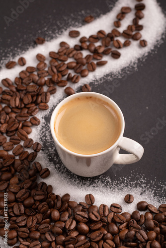 photo a cup of espresso surrounded by aromatic coffee beans, creating a visually pleasing background. With a touch of sugar, it promises a delightful coffee experience captured in this image.
