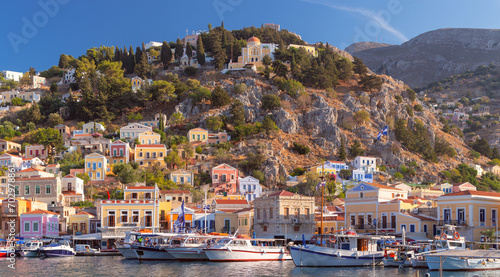 Multi-colored facades of houses in the village of Symi at sunset.