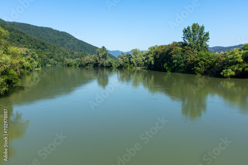 River with muddy green water, against the background of trees and hills