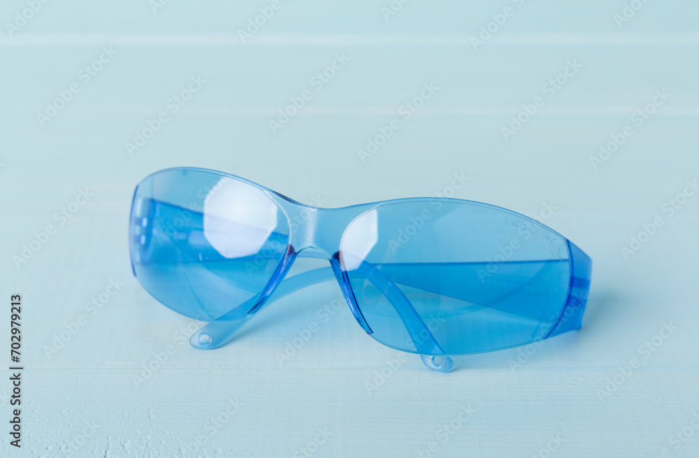 Blue safety glasses on wooden table Blue safety glasses on wooden table