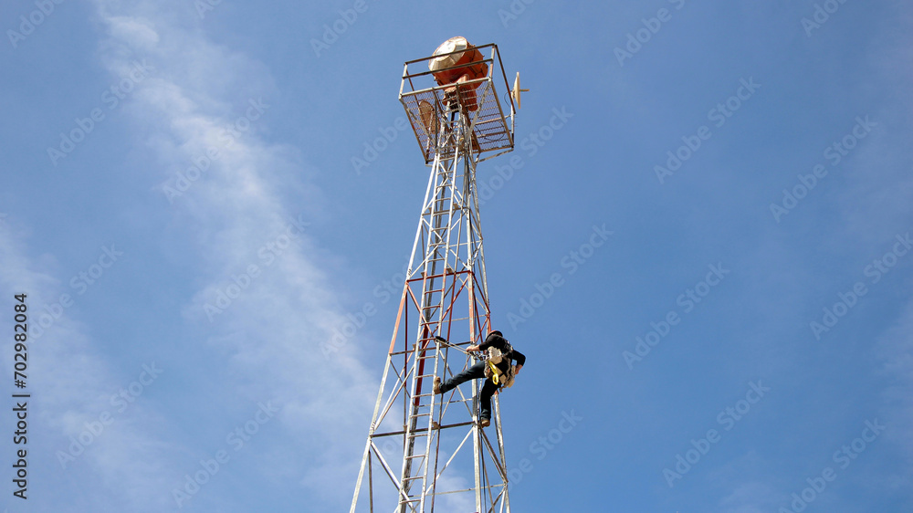 DoD tower technician climbing tower to make repairs